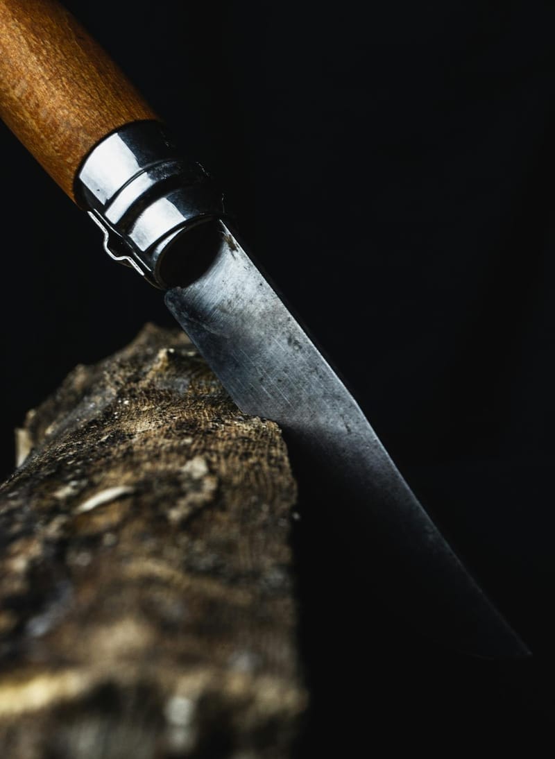 Folding knife in wood, chiaroscuro lighting