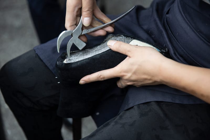 Cobbler working leather with a plier in his workshop