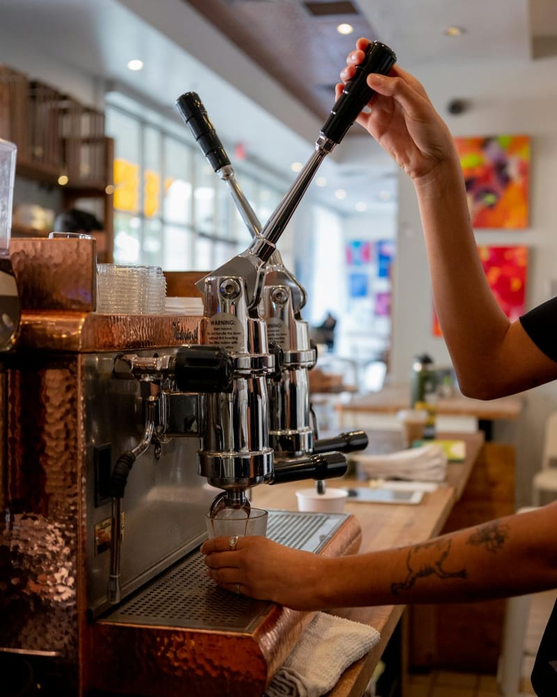 Barista using a lever espresso machine in a café
