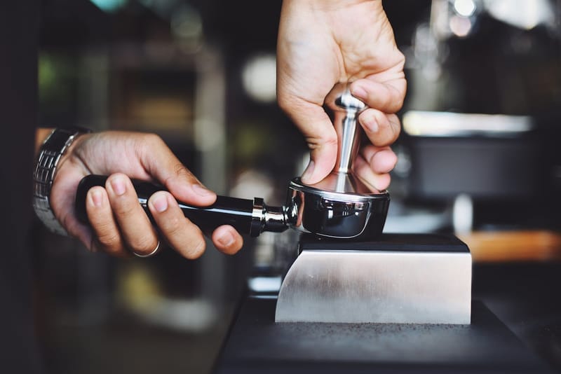 Barista tamping ground coffee in a portafilter