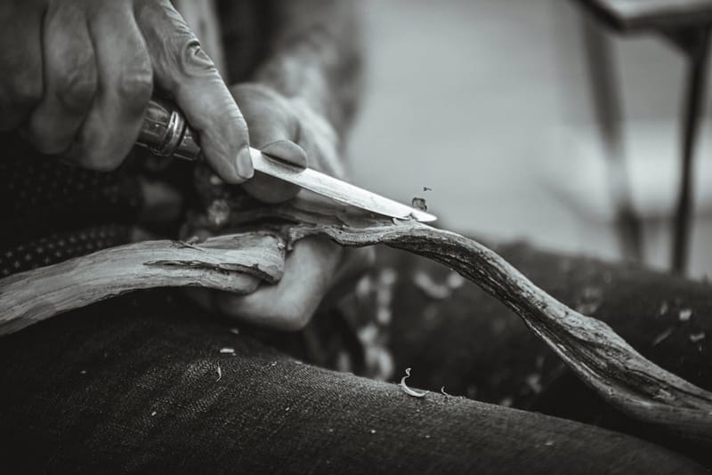 Craftsman carving with a knife, black and white
