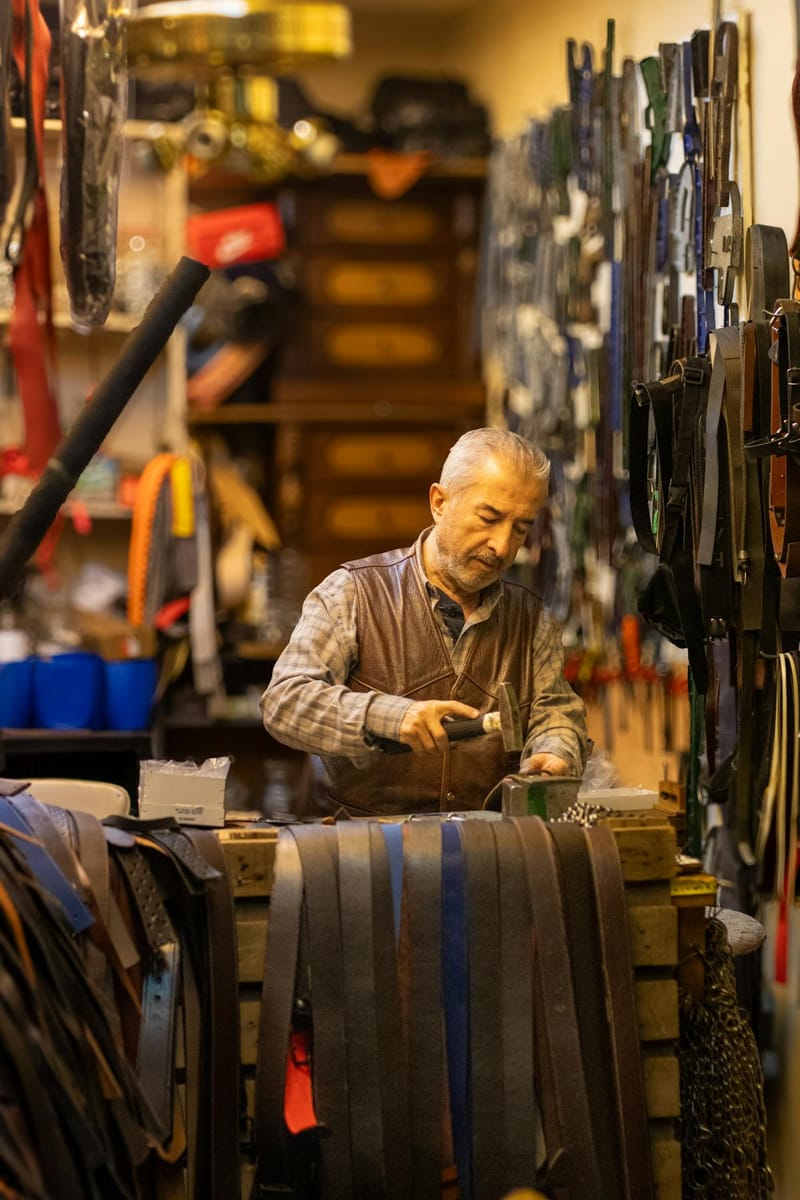 Belt maker in his lifelong workshop, stacked leathers and tools