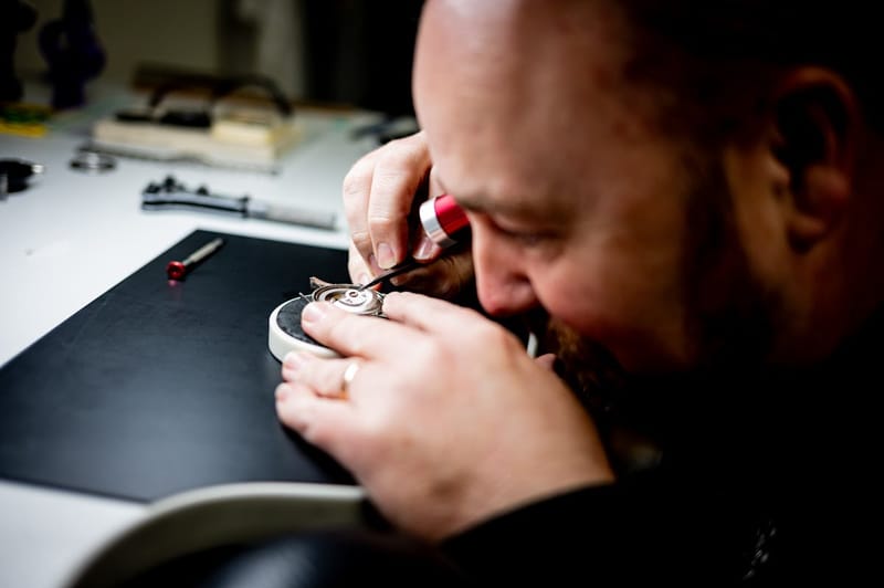 Horloger examinant un mouvement mécanique avec précision