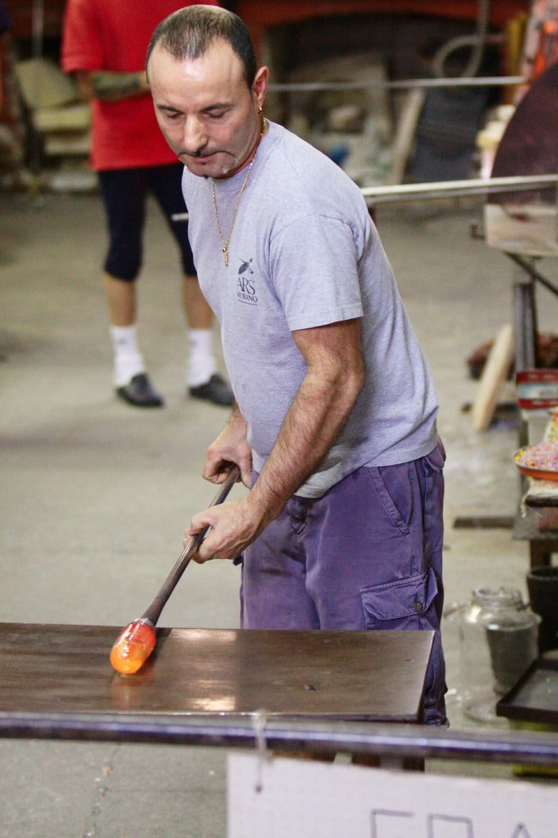 Maître verrier de Murano soufflant le verre dans sa verreria